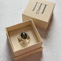 Handmade sterling silver double band ring featuring a one-of-a-kind oval moss agate gemstone with deep forest green inclusions. Contemporary artisan statement ring by Journey Through Jewellery, presented in a cream jewellery box with a mirror-polished finish.