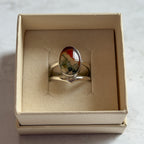 Pair of handcrafted sterling silver stud earrings with oval moss agate and carnelian gemstones, displayed in a cream Journey Through Jewellery gift box. Each one-of-a-kind gemstone features unique amber, green and black landscape-like inclusions, finished with mirror-polished bezels and handcrafted silver grain details.