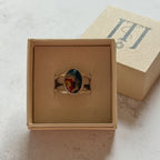 Handmade sterling silver double band ring featuring an oval moss agate and carnelian gemstone with a vivid natural red inclusion. One-of-a-kind artisan statement ring by Journey Through Jewellery, displayed in a cream jewellery box with a polished finish.